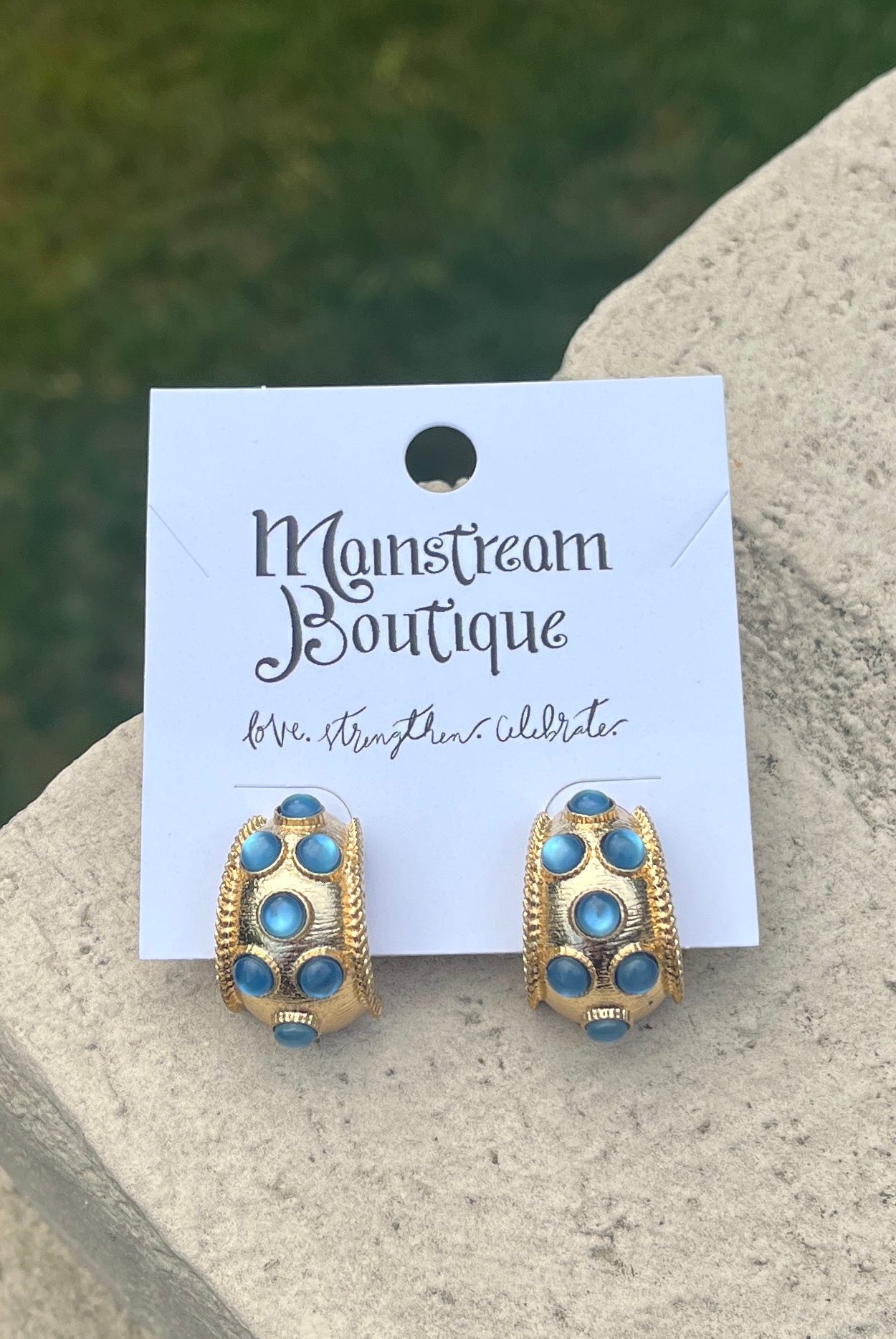 Gold and blue earrings against a stone background