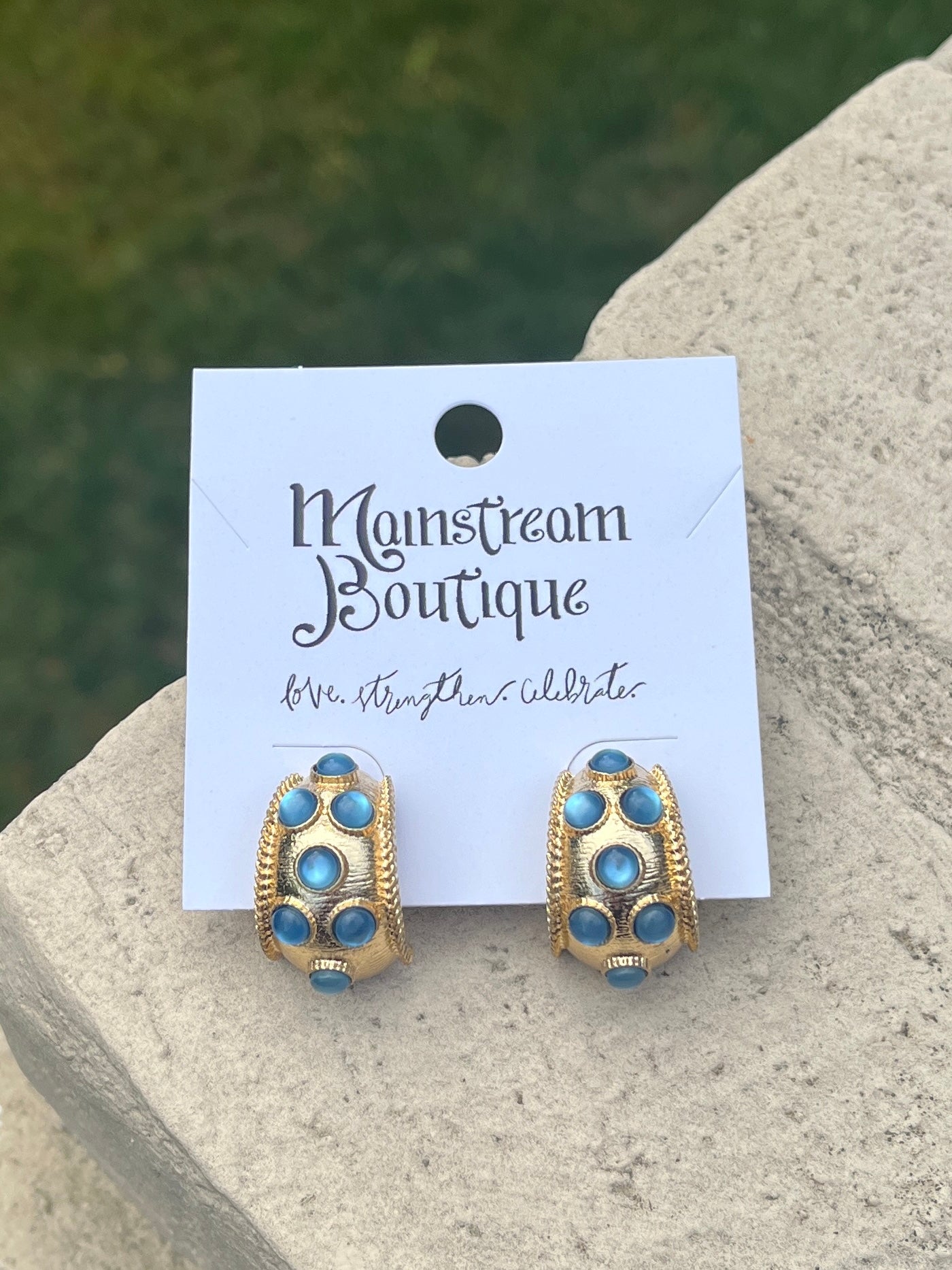 Gold and blue earrings against a stone background