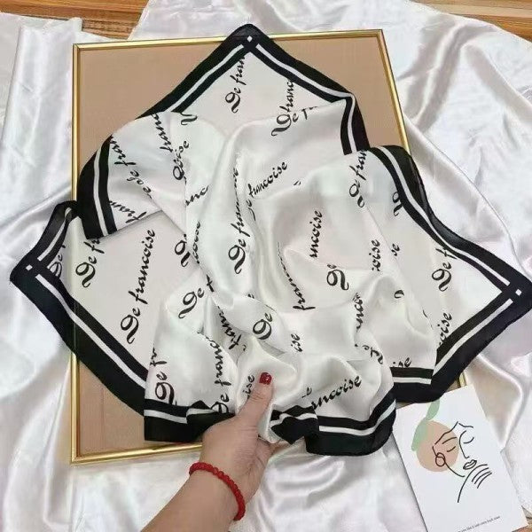 White scarf with black text held by a hand on a white surface