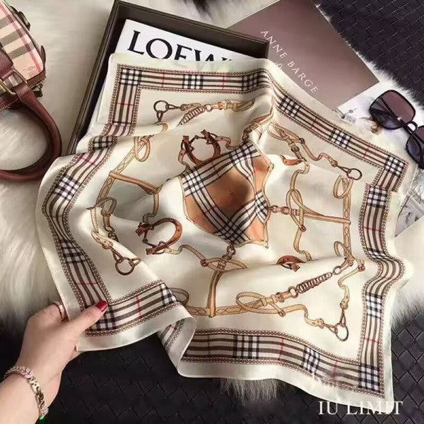 Burberry scarf with horse and harnais pattern held by a hand on a textured surface.
