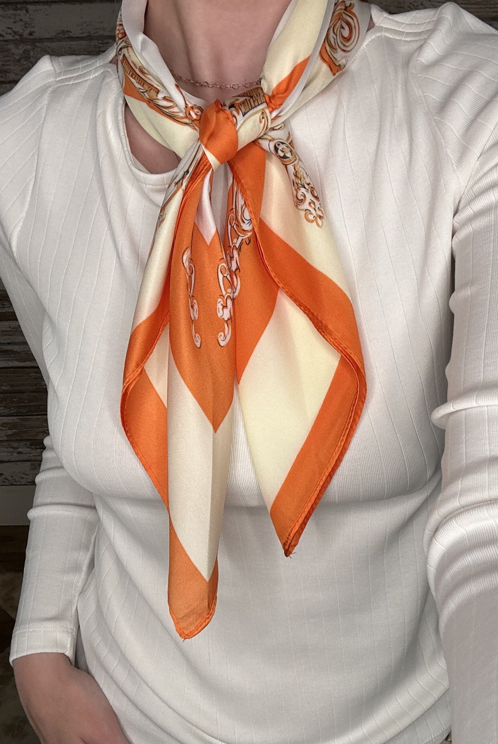 Silky orange and cream printed neck scarf featuring an ornate geometric design with a satin finish.