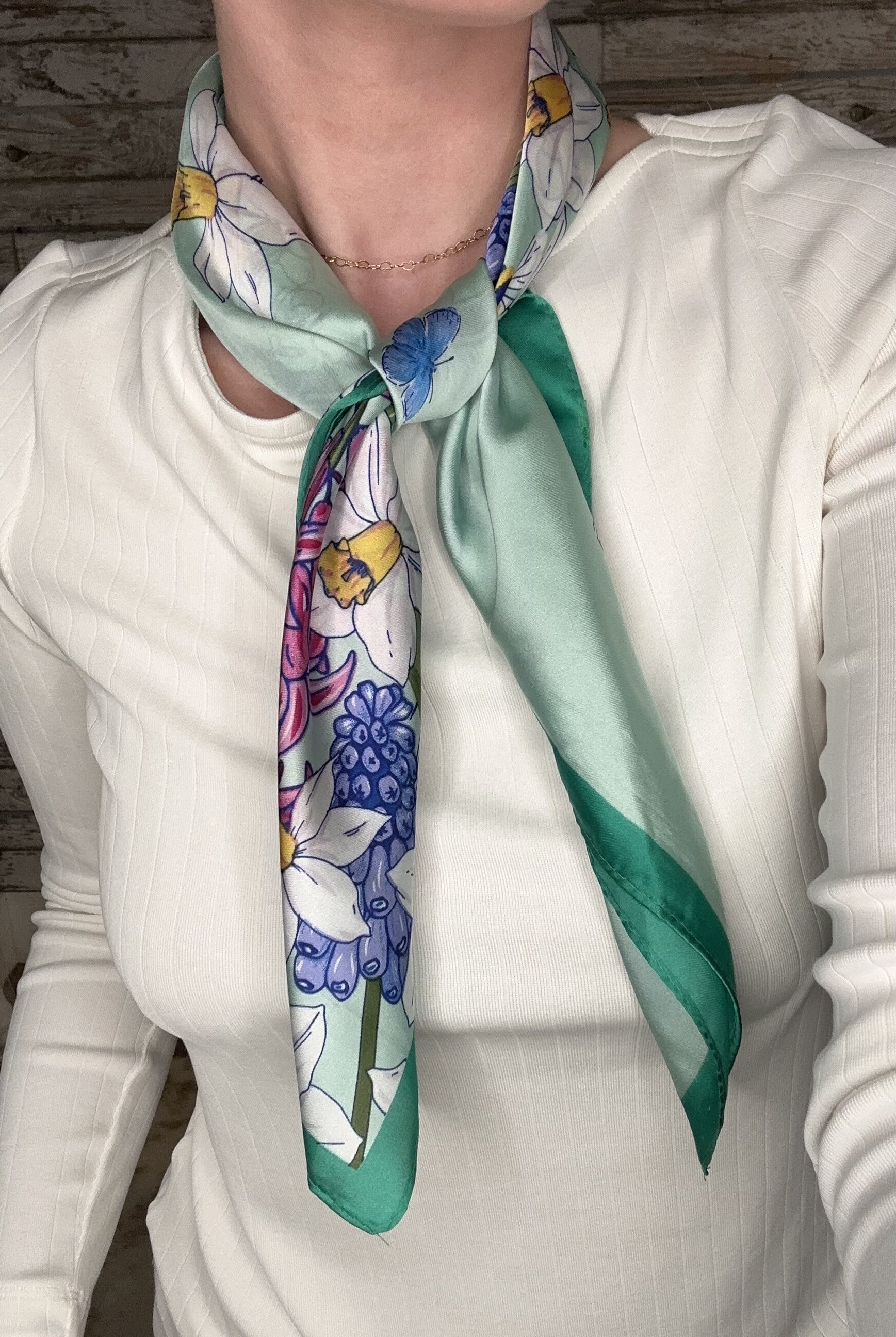 Silky green botanical neck scarf featuring colorful floral prints and a soft satin finish.