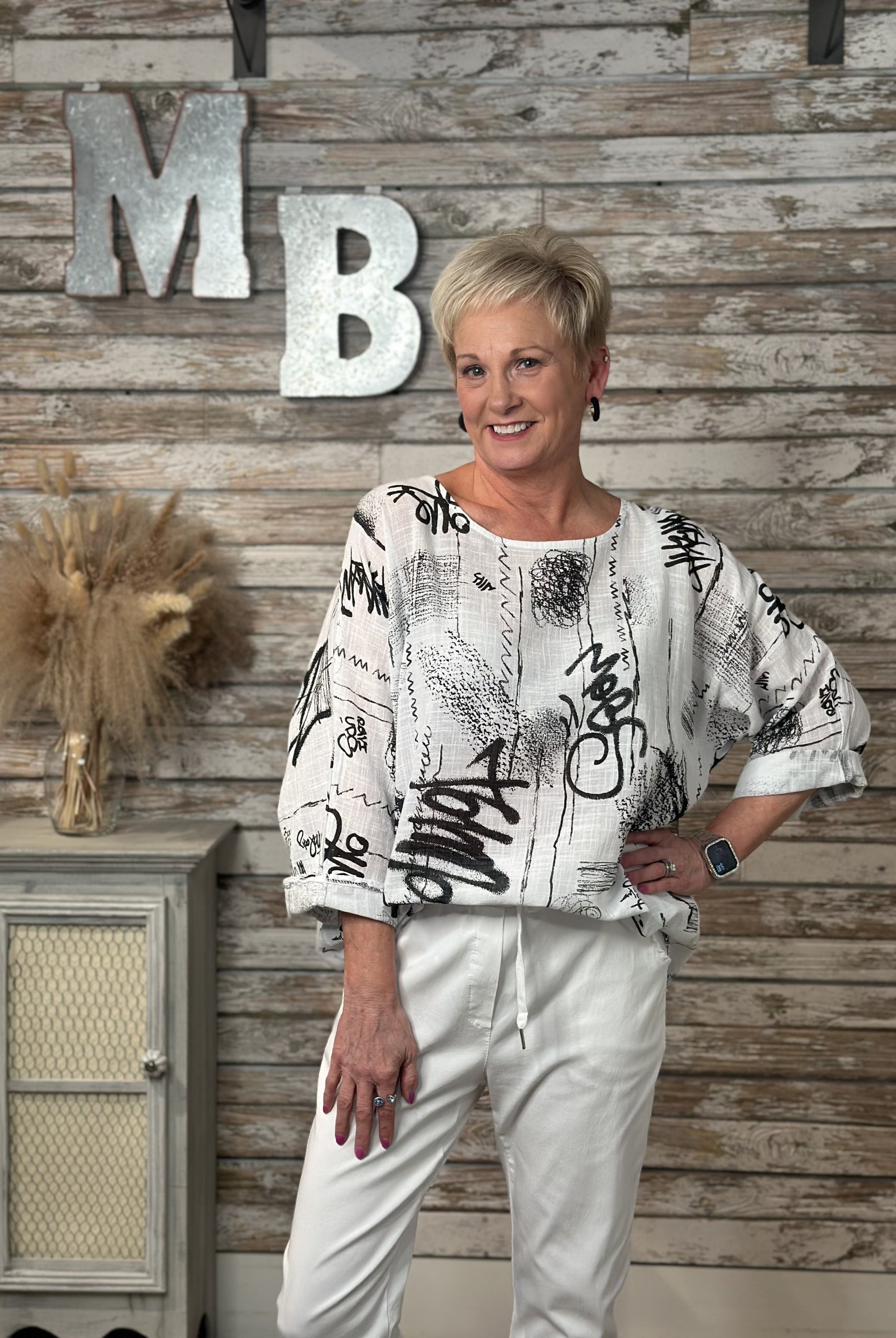 Woman standing in front of a wooden wall with decorative letters and a cabinet.