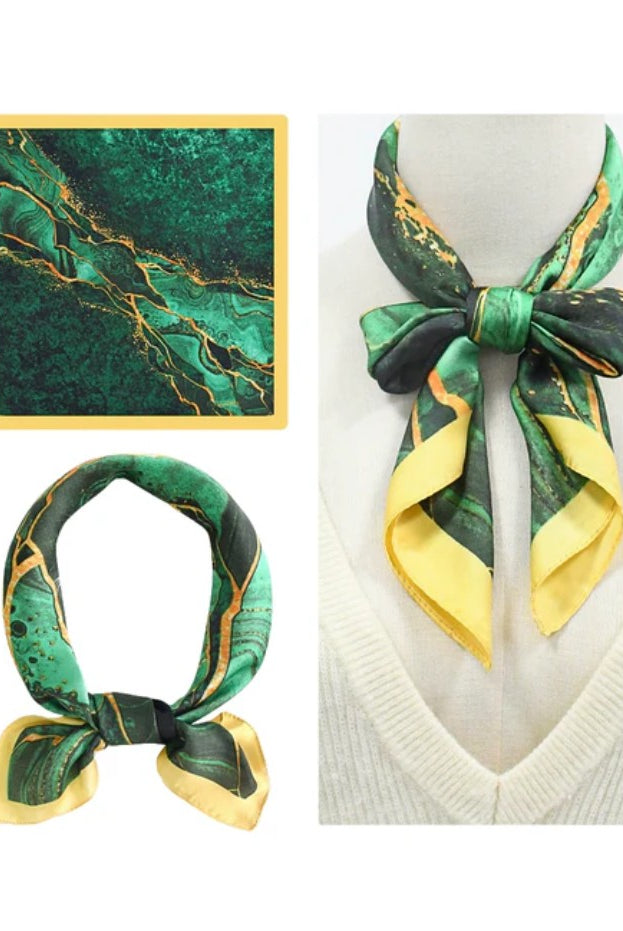 Green and yellow patterned scarf on a mannequin and flat surface with a marble background.