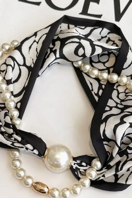 Black and white patterned headband with pearls on a white background