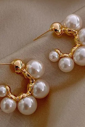 Gold hoop earrings with pearls on a beige background