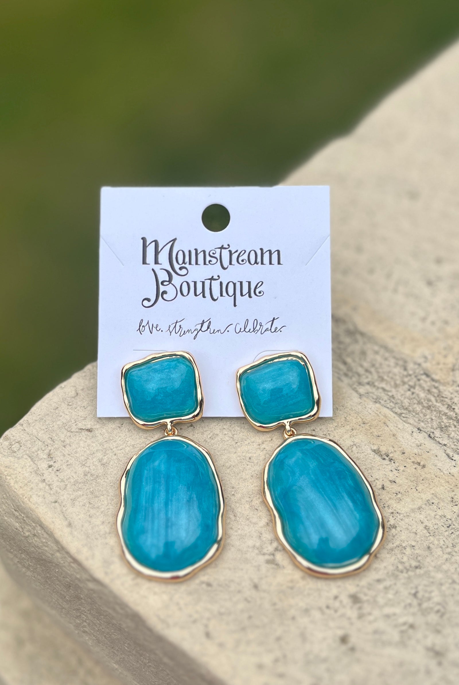 Turquoise earrings on against a blurred natural background