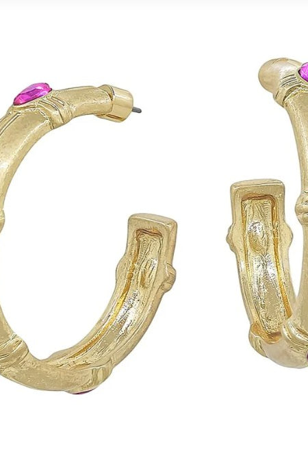 Gold hoop earrings with pink gemstones on a white background