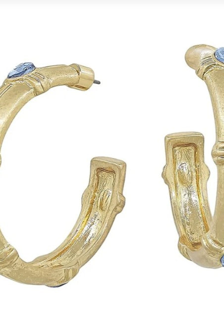 Gold hoop earrings with blue gemstones on a white background