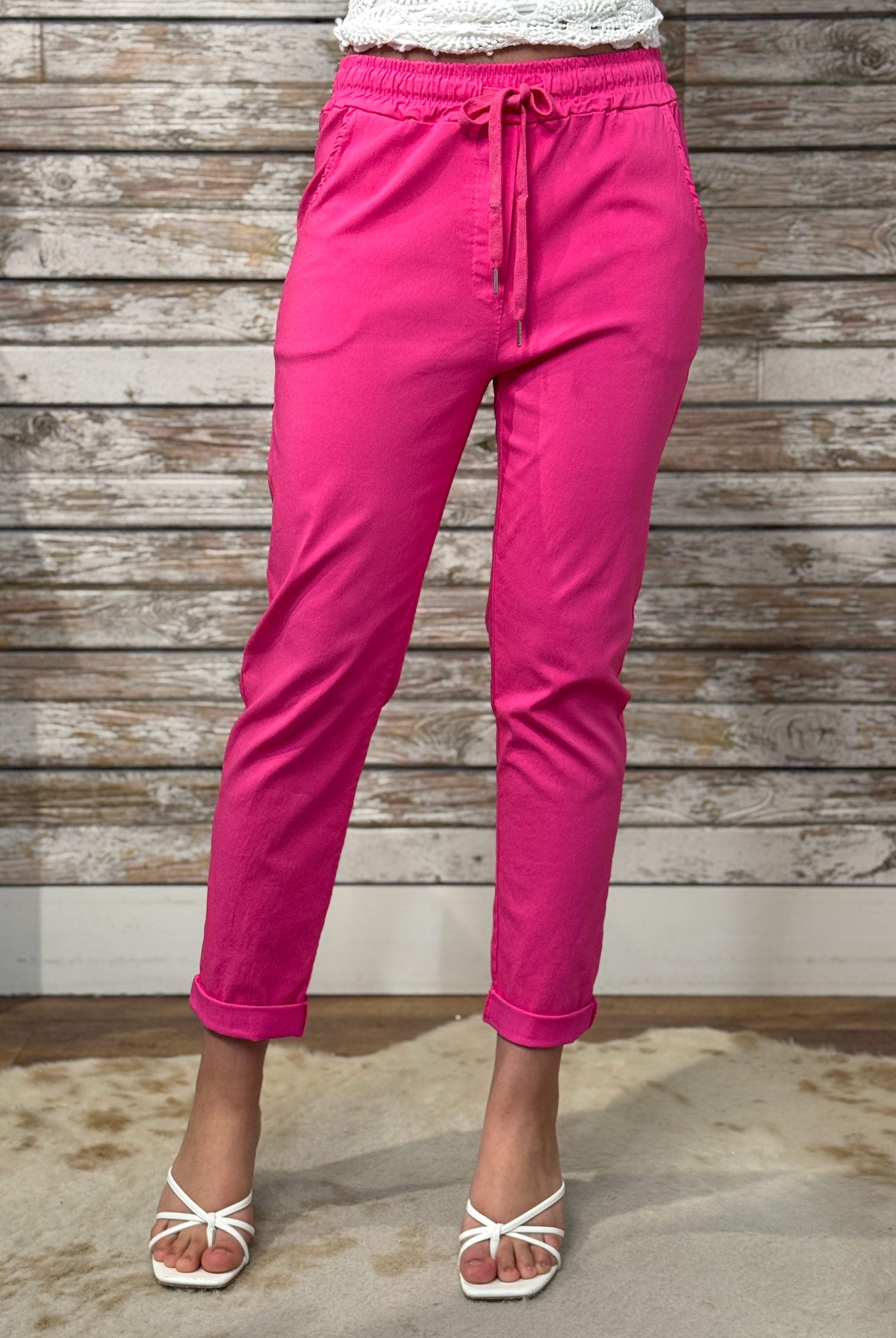 Person wearing bright pink pants against a wooden wall.