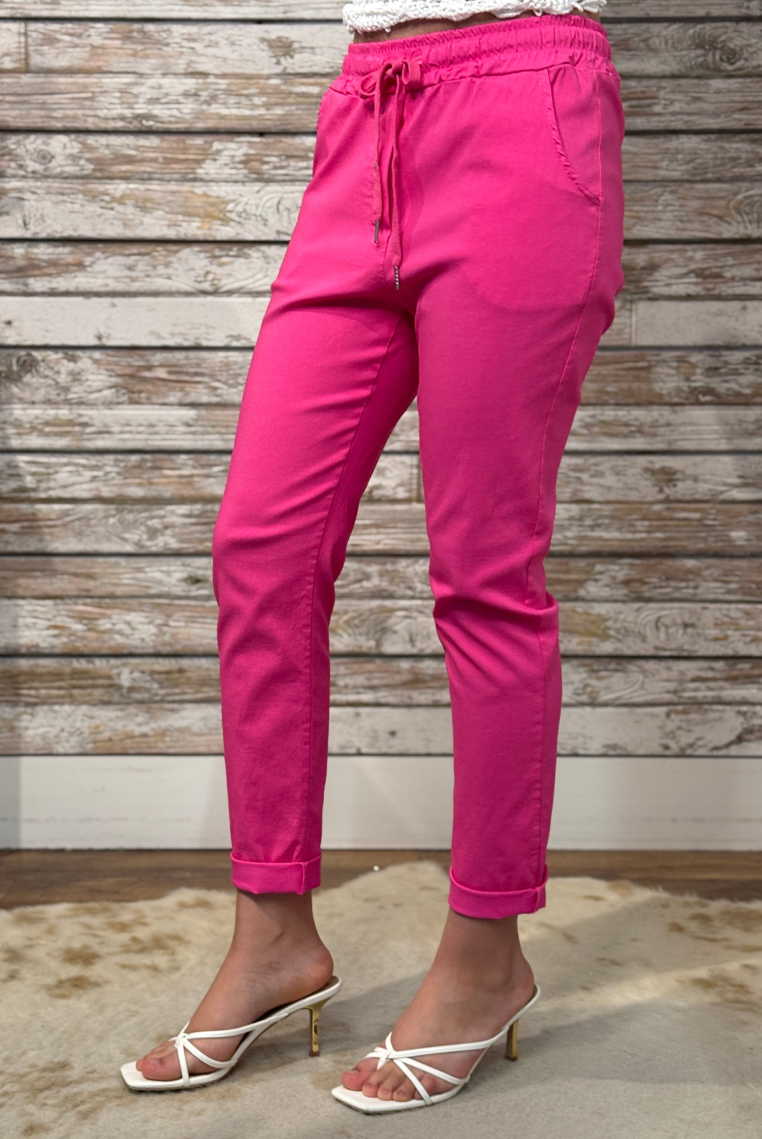 Person wearing bright pink pants with a wooden background