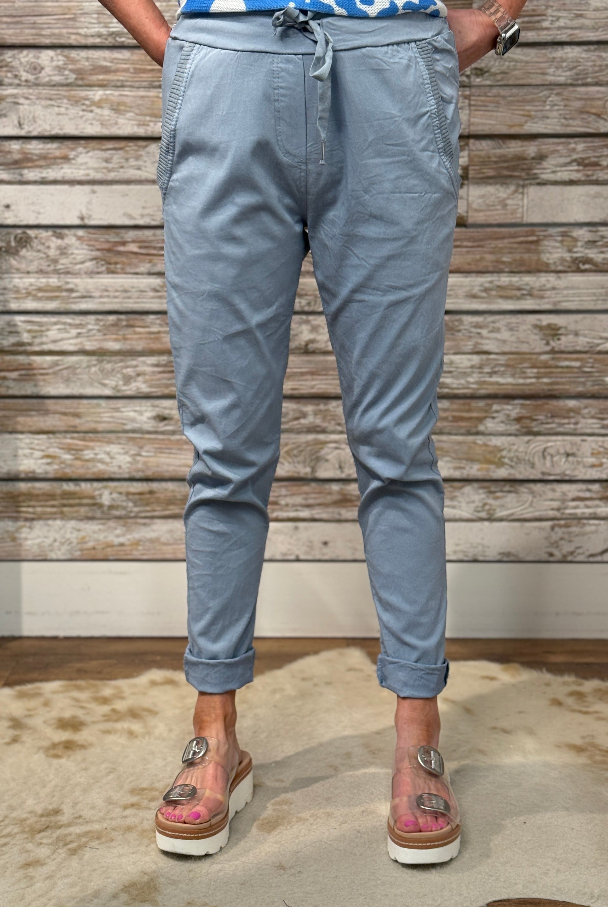 Person wearing light blue pants with a wooden wall background