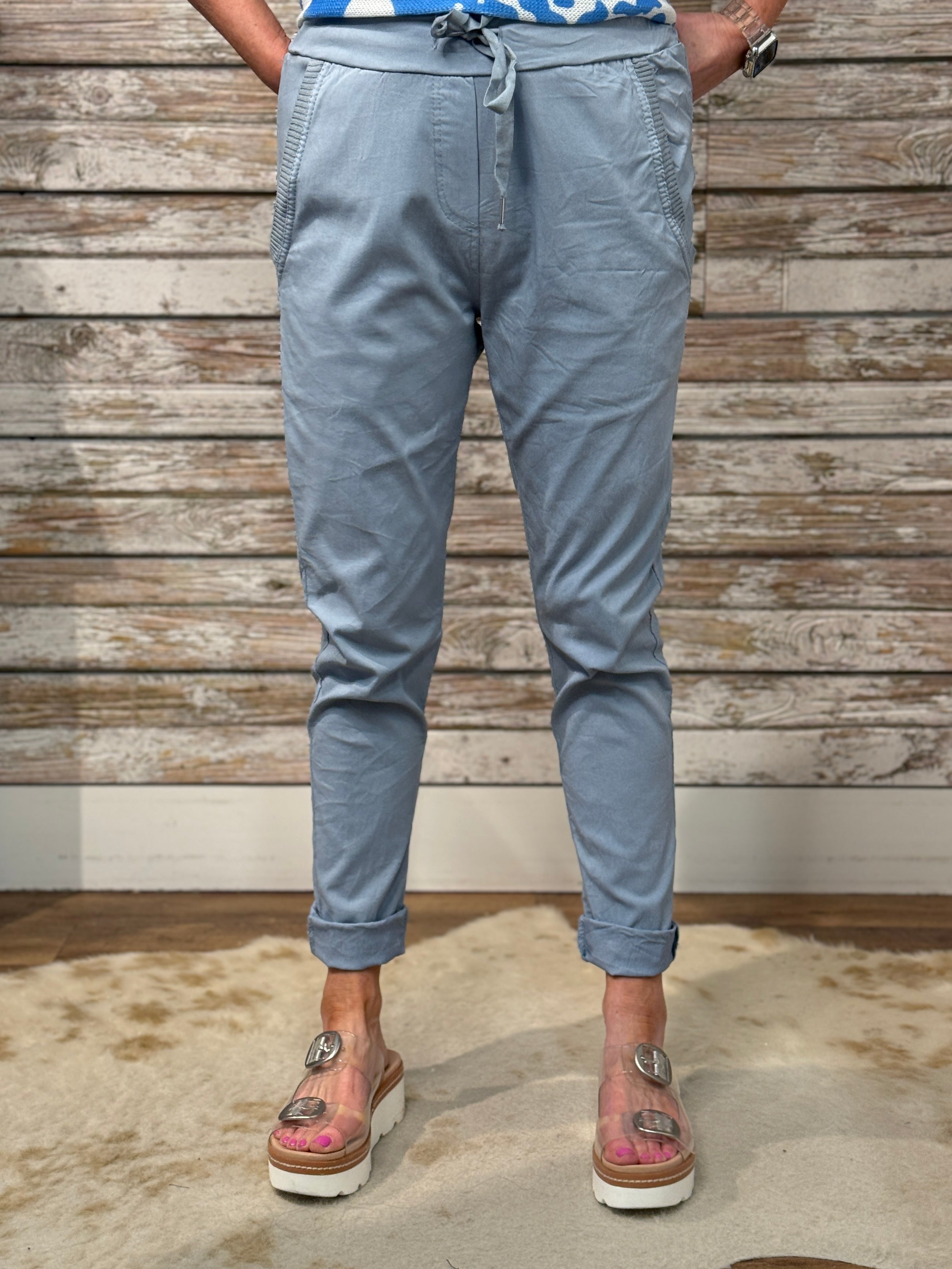 Person wearing light blue pants with a wooden wall background