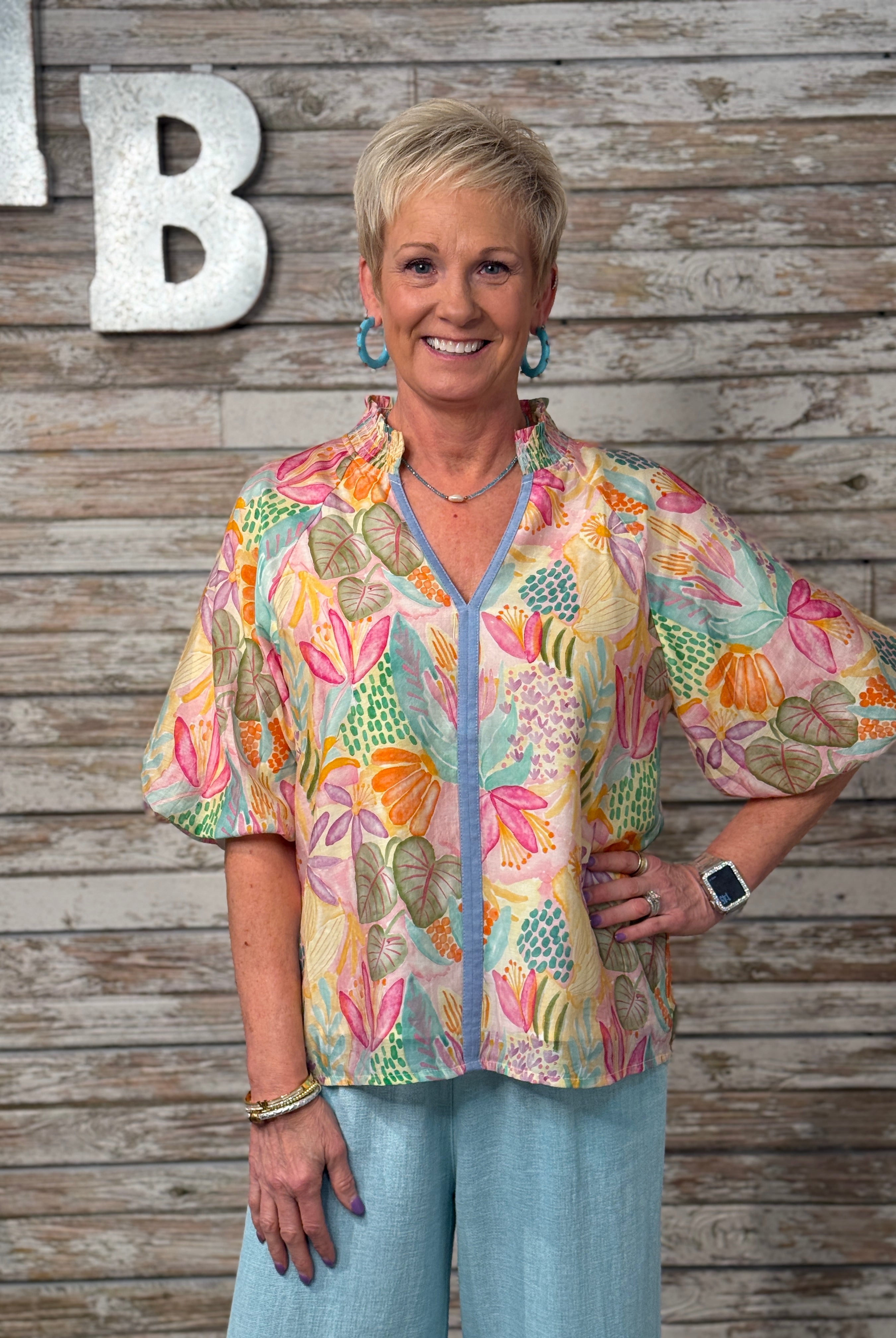Woman wearing a colorful floral blouse against a wooden background