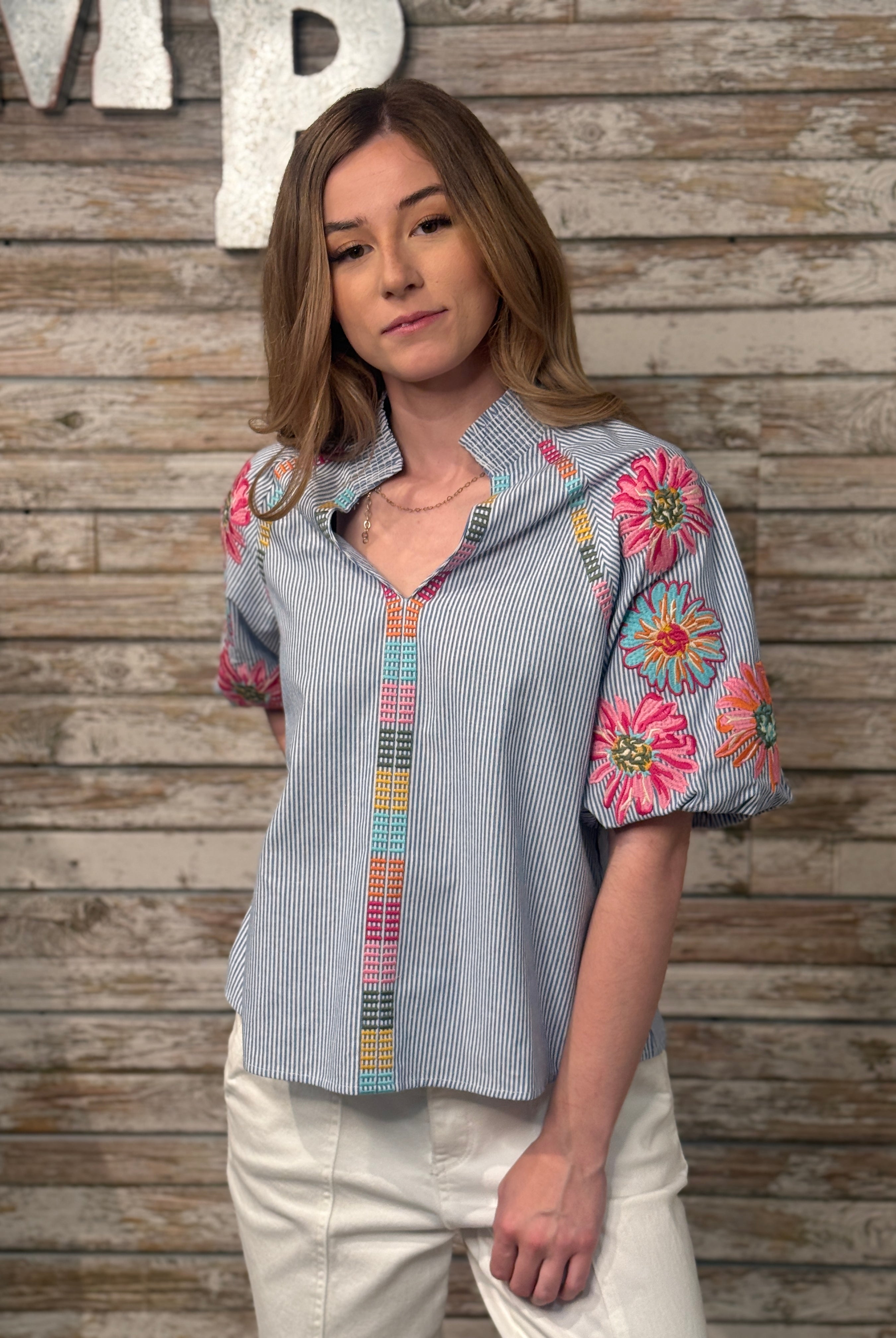 Woman wearing a colorful embroidered shirt against a wooden background