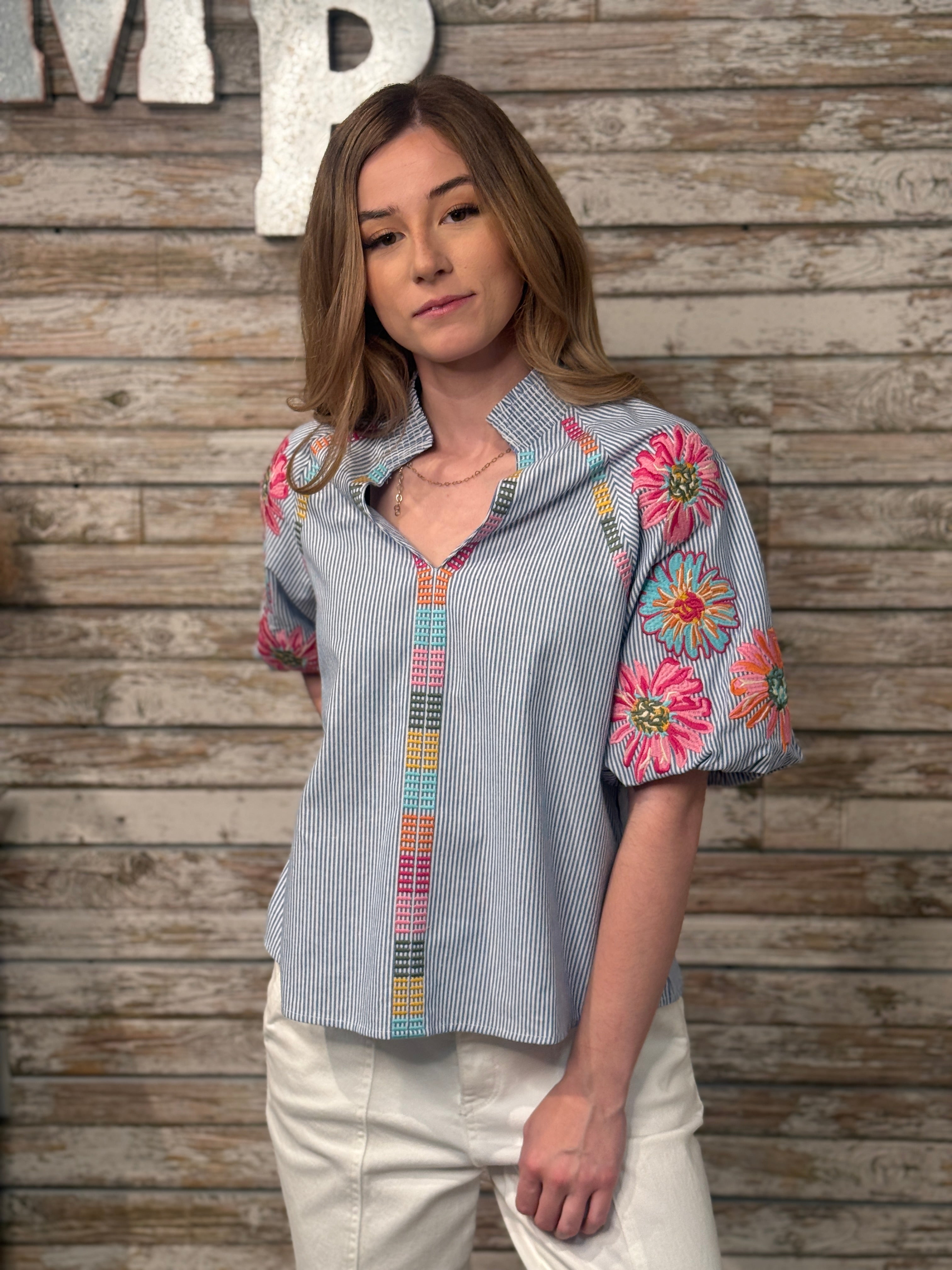 Woman wearing a colorful embroidered shirt against a wooden background