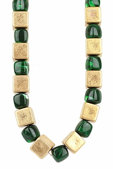 Bracelet with alternating green and gold square beads on a white background