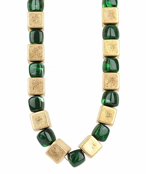 Bracelet with alternating green and gold square beads on a white background