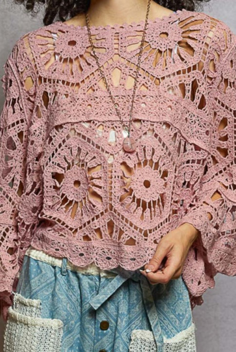 Pink crochet top worn by a person against a gray background