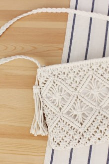 White crochet handbag with tassel on a wooden surface
