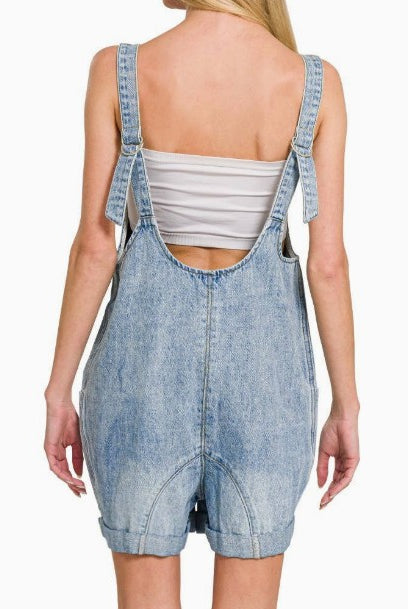 Denim overalls worn by a person on a white background