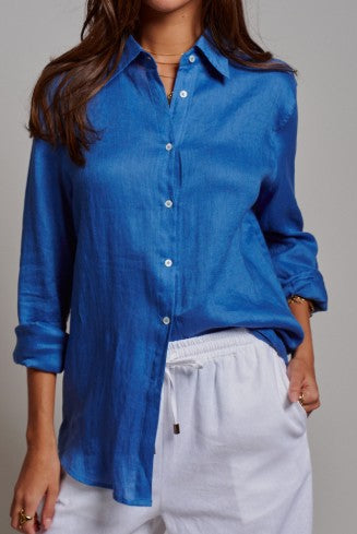 Person wearing a blue shirt and white pants against a gray background