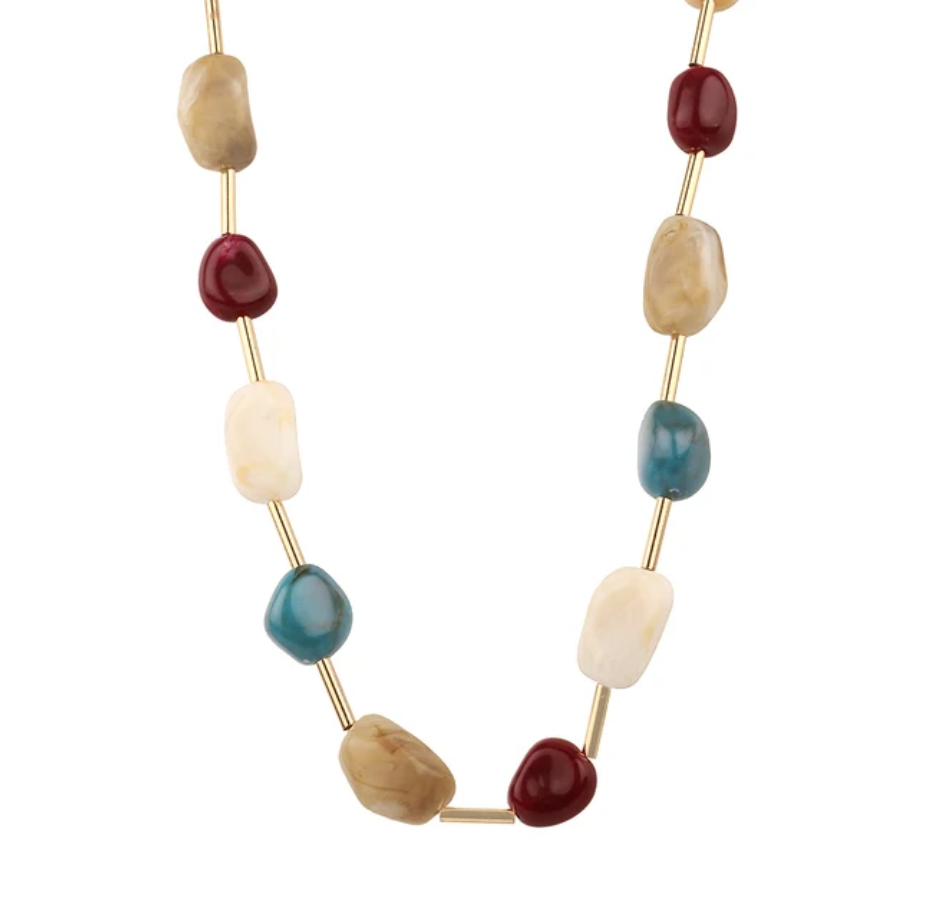 A gold-tone beaded necklace featuring alternating smooth, polished stone beads in cream, tan, deep red, teal blue, and light blue, displayed on a clean white background.