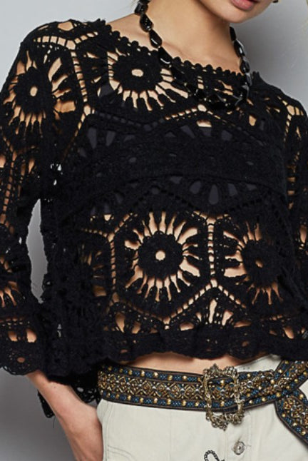 Black crochet top worn by a person on a plain background