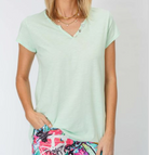 Person wearing a light green t-shirt with colorful shorts on a plain background