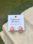 Pair of pink and gold earrings against a natural background.