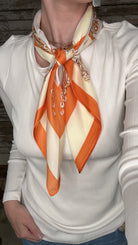 Silky orange and cream printed neck scarf featuring an ornate geometric design with a satin finish.