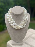 White pearl necklace on a gray bust with a blurred green background