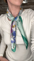 Silky green botanical neck scarf featuring colorful floral prints and a soft satin finish.