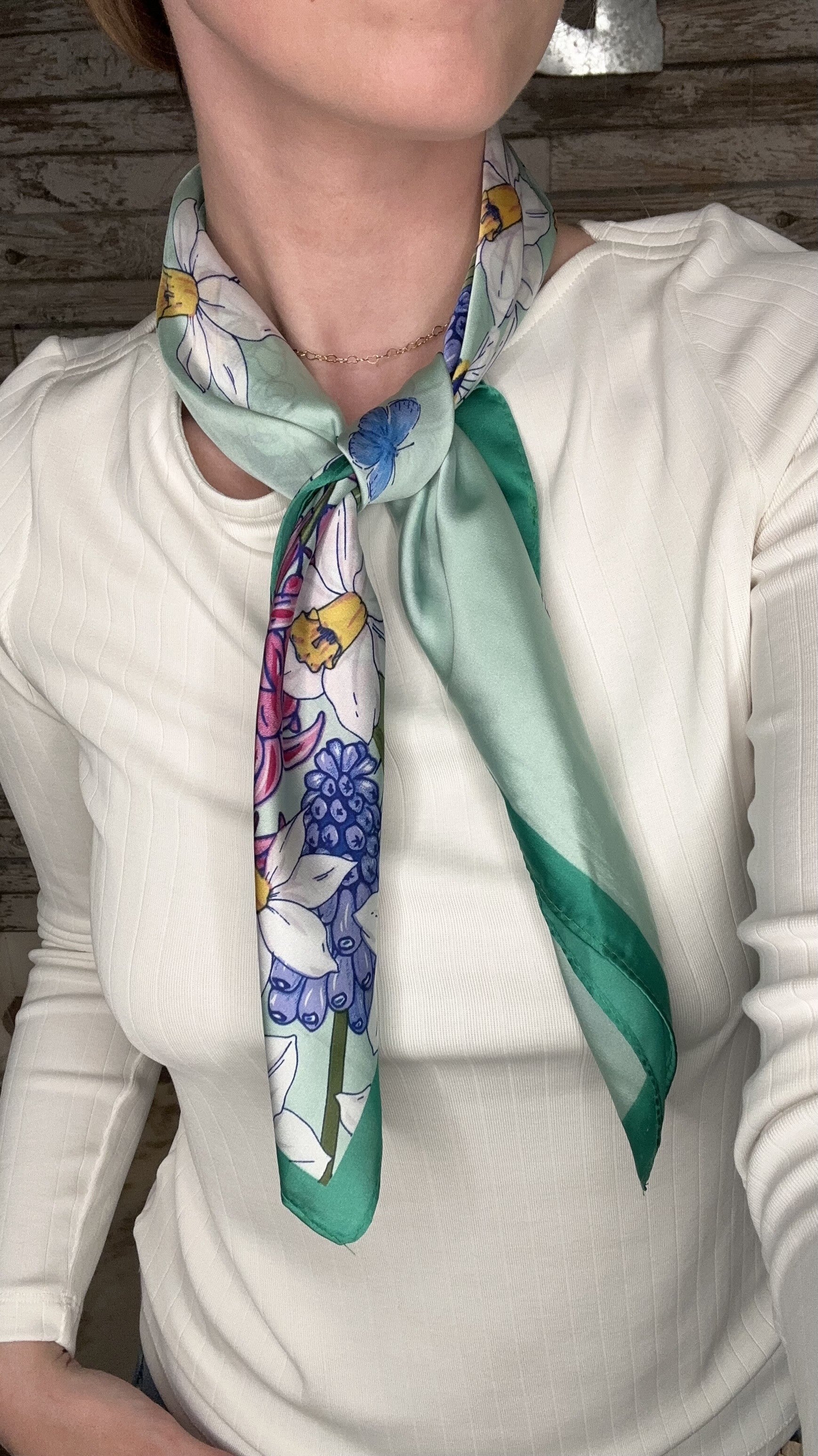Silky green botanical neck scarf featuring colorful floral prints and a soft satin finish.