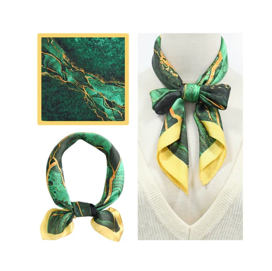 Green and yellow patterned scarf on a mannequin and flat surface with a marble background.