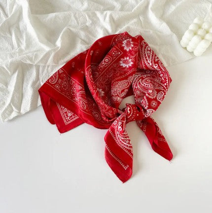 Red bandana with white patterns on a white fabric background