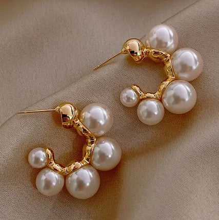 Gold hoop earrings with pearls on a beige background