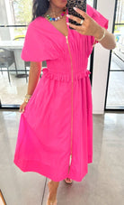 Person wearing a bright pink dress with a blurred indoor background
