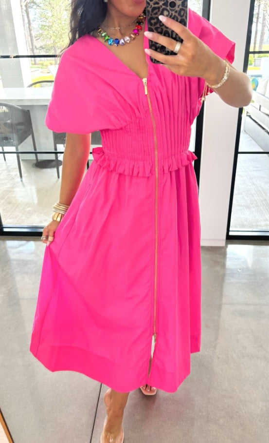 Person wearing a bright pink dress with a blurred indoor background