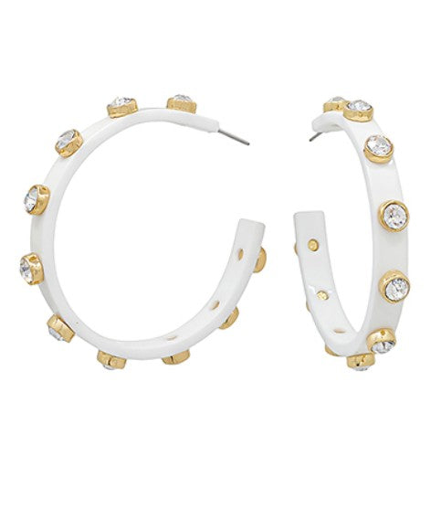 White hoop earrings with gold accents and clear stones on a white background