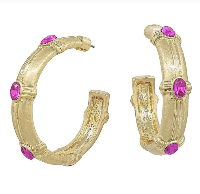 Gold hoop earrings with pink gemstones on a white background