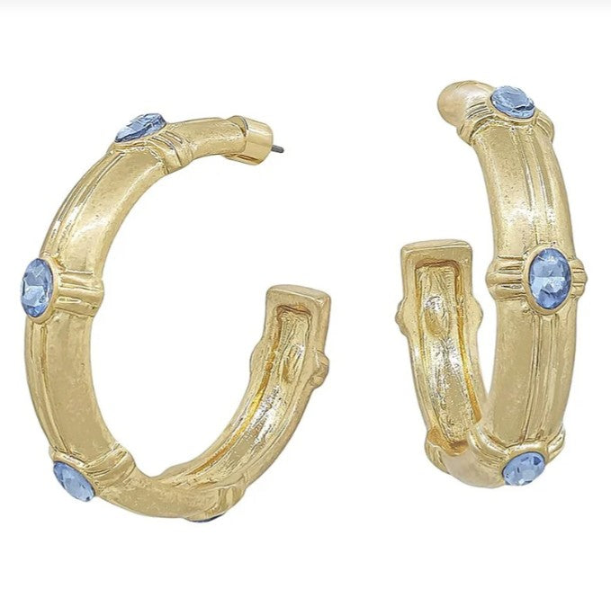 Gold hoop earrings with blue gemstones on a white background