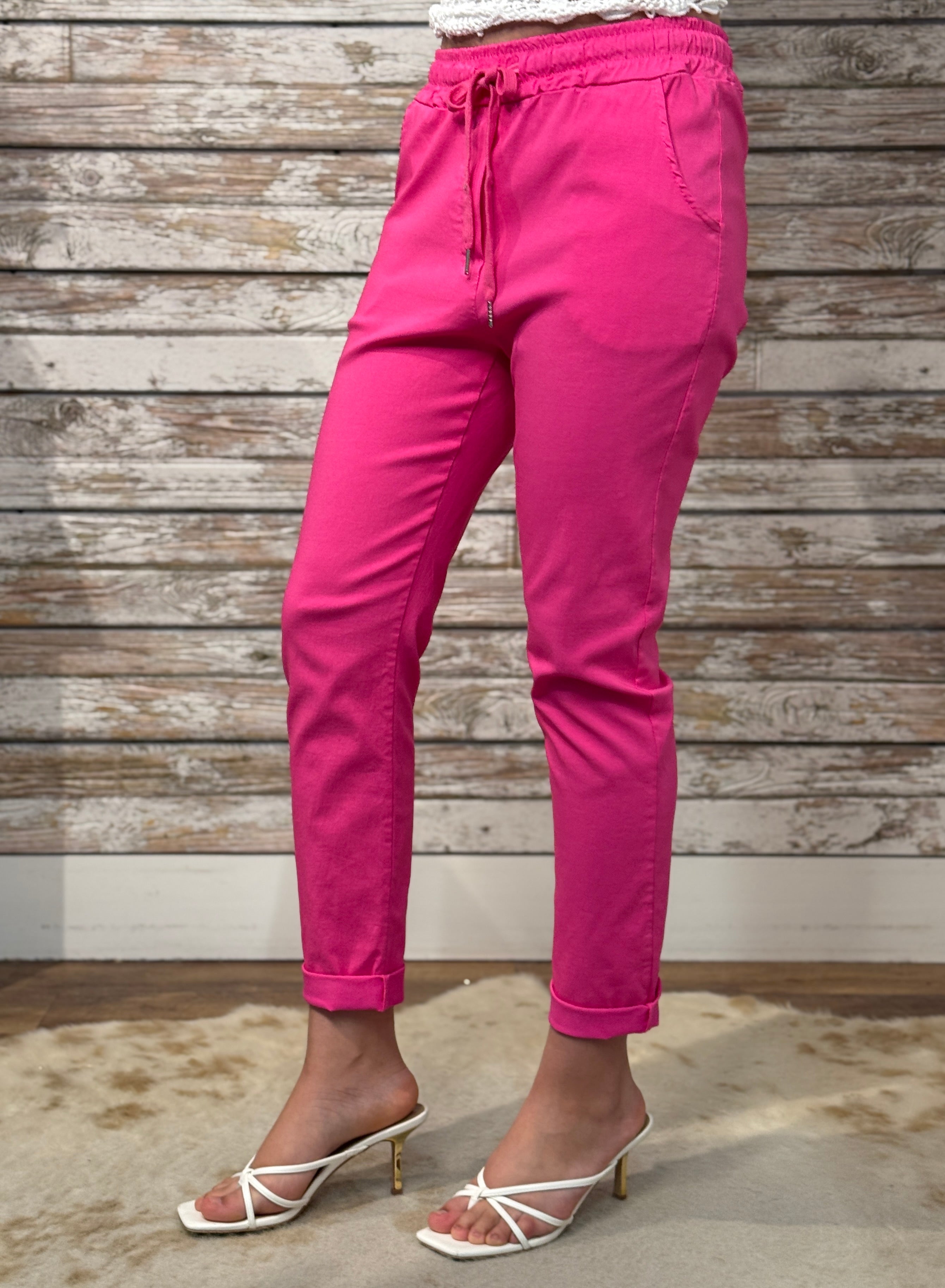 Person wearing bright pink pants with a wooden background