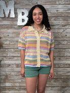 Woman wearing a colorful striped shirt against a wooden background