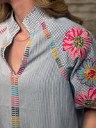Close-up of a shirt with floral embroidery and colorful patterns.
