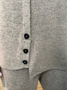 Close-up of a knit garment with three black buttons down the front, showing the fabric texture and button details.