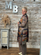 A woman wearing a long-sleeved abstract print cardigan over a brown top and matching pants.