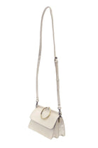 White handbag/crossbody with a gold ring handle on a white background