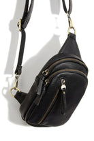 Black leather crossbody bag with gold zippers on a white background