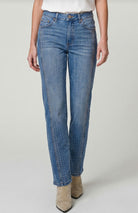 Person wearing blue jeans with gold studs on a plain background